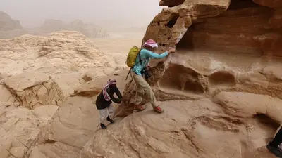 two people walking on a rock in the desert at Wadi Rum Backpacker Camp in Wadi Rum