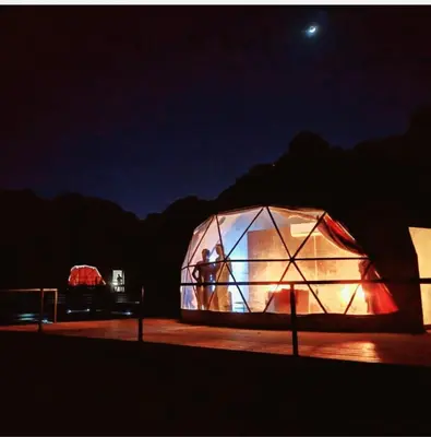 a couple of people in a greenhouse at night at Enjoy Camp Bubble Luxury with Jeep Tour in Wadi Rum