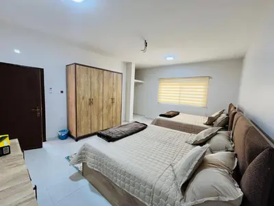 a bedroom with two beds and a wooden cabinet at marram apartment in Aqaba