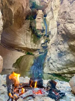 a camp fire in front of a waterfall at Dana star in Dana