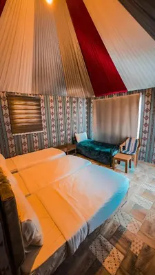a bedroom with a large bed and a chair at Nada luxury camp in Wadi Rum