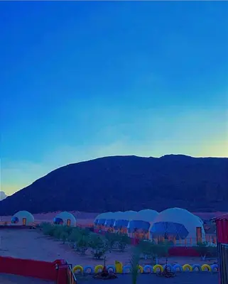 a group of tents in the desert with mountains in the background at Khaled Rum Camp in Disah