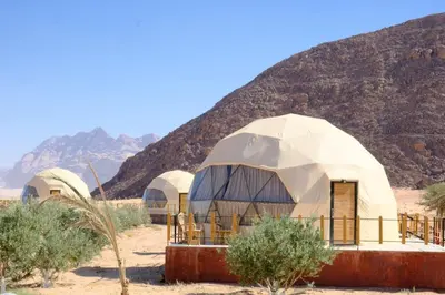 a group of domes in the desert with a mountain at Khaled Rum Camp in Disah