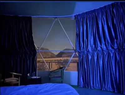 a bedroom with blue curtains and a bed and a window at Khaled Rum Camp in Disah