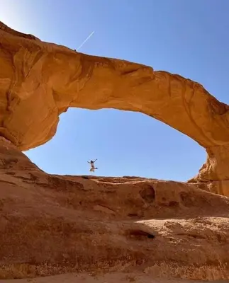 a plane flying through an arch in the desert at Faiesal Luxury camp & Tour in Wadi Rum
