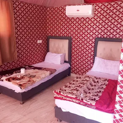 two beds sitting next to each other in a room at Faiesal Luxury camp & Tour in Wadi Rum
