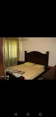 a bedroom with a bed with a wooden head board at ستيديوهات مفروشة و مطلة في طابق ثالث و الرابع in Amman