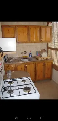 a kitchen with a white stove and wooden cabinets at ستيديوهات مفروشة و مطلة في طابق ثالث و الرابع in Amman