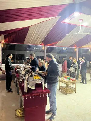 a group of people standing around a table with food at Rum Star Desert Camp in Wadi Rum