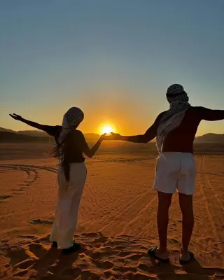 two people standing in the desert watching the sunset at Rum Star Desert Camp in Wadi Rum