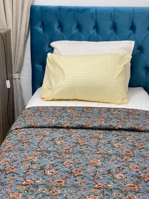 a bed with a blue headboard and a yellow pillow at Beautiful & Cozy Newly remodeled 2 Bedroom in Amman