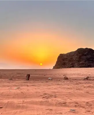 a sunset in the desert with a rock formation at Wadi Rum Faris in Wadi Rum