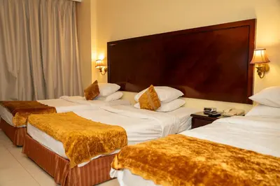 a hotel room with three beds and a large headboard at JAZEERAT QUBTAN in Aqaba