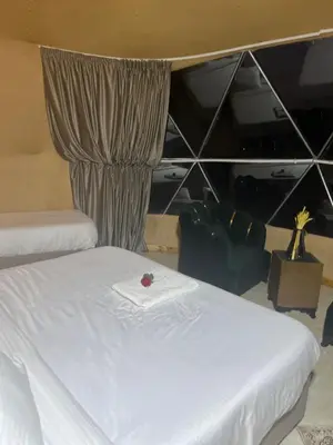 a bedroom with a bed with a white blanket and a curtain at 7stars in Disah