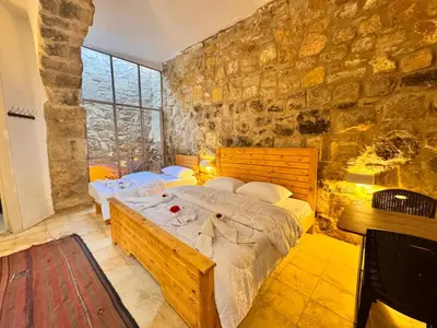 a bedroom with two beds and a stone wall at family home Lodge in Dana