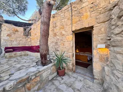 a stone building with a tree in the doorway at family home Lodge in Dana