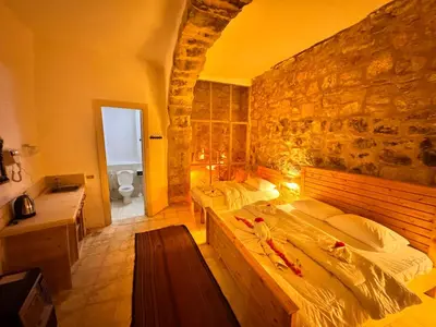 a bedroom with two beds and a stone wall at family home Lodge in Dana