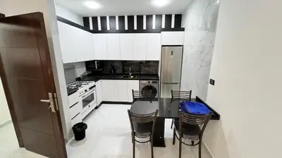 a kitchen with white cabinets and a table and chairs at شقة بغرفه نوم واحدة عمو سامي in Amman