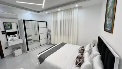 a white bedroom with a large bed and a mirror at شقة بغرفه نوم واحدة عمو سامي in Amman