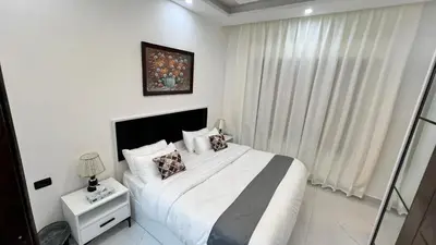 a white bedroom with a large bed and a picture on the wall at شقق عمو سامي بغرفة نوم 1 in Amman