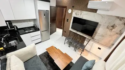 a living room with a large television and a kitchen at شقق عمو سامي بغرفتين نوم 2 in Amman