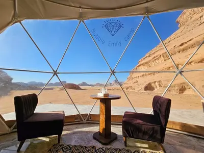 a tent with two chairs and a table in the desert at Bubble Emily camp in Wadi Rum
