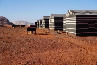 a row of black and white buildings in the desert at Moon shine camp in Wadi Rum