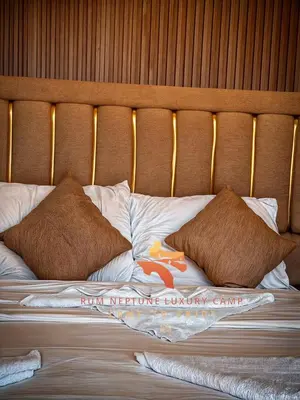 a bed with brown pillows and a wooden headboard at RUM NEPTUNE lUXURY CAMP in Wadi Rum