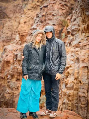 a man and a woman standing next to a mountain at RUM NEPTUNE lUXURY CAMP in Wadi Rum