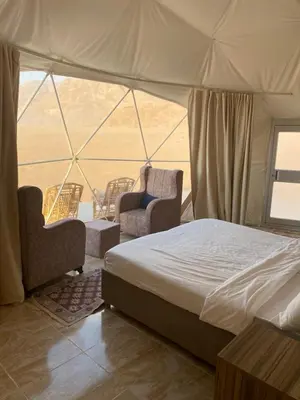 a bedroom with a bed and chairs in a tent at Desert Elegance Luxury Bedouin Camp Panoramic View in Wadi Rum