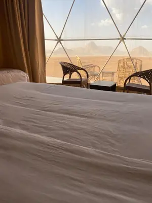 a bed and chairs in a room with a view of the desert at Desert Elegance Luxury Bedouin Camp Panoramic View in Wadi Rum