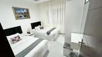a white bedroom with two beds and a window at شقة بثلاث غرف نوم 3 عمو سامي in Amman