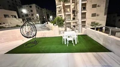 a patio with a table and chairs on a green lawn at شقة بثلاث غرف نوم 3 عمو سامي in Amman