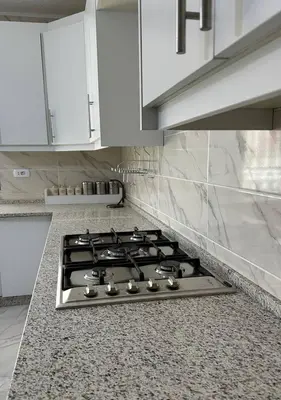a stove top in a kitchen with white cabinets at Tlaa al ali amman 3 rooms furnished apartment المحكمة الدستورية in Umm Uthainah