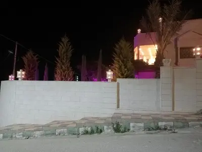 a white brick wall in front of a house at night at Bait al salam in Um Qeis