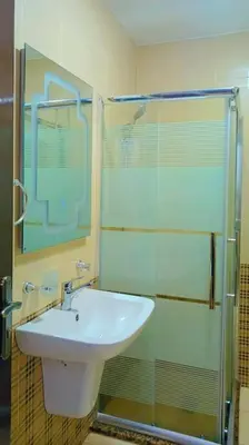 a bathroom with a sink and a glass shower at شقة فاخرة واسعة في شارع المدينة المنورة in Umm Uthainah