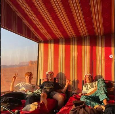 three men sitting on beds in a room with a window at Wadirum sunset camp in Wadi Rum
