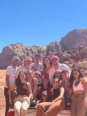 a group of people posing for a picture in the desert at Wadirum sunset camp in Wadi Rum