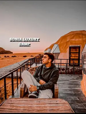 a man sitting on a boardwalk next to the beach at sonia luxury camp in Wadi Rum