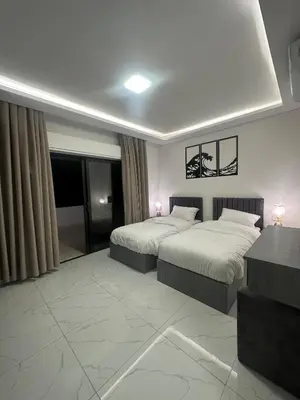 a hotel room with two beds and a table at Cozy and Tranquil Rooftop Near Al Services 23 in Amman