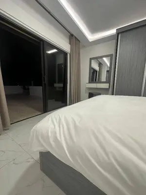a bedroom with a large white bed and a tv at Cozy and Tranquil Rooftop Near Al Services 23 in Amman
