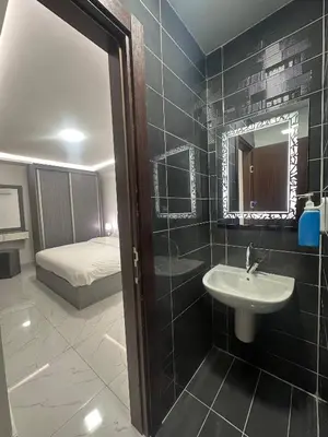 a bathroom with a sink and a mirror and a bed at Cozy and Tranquil Rooftop Near Al Services 23 in Amman