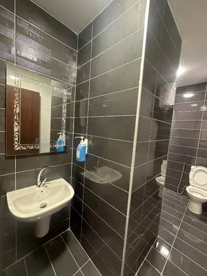 a black tiled bathroom with a sink and a toilet at Cozy and Tranquil Rooftop Near Al Services 23 in Amman