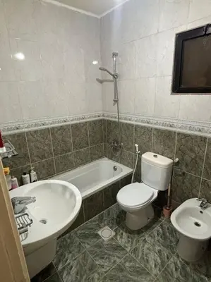 a bathroom with a toilet and a tub and a sink at Zahrat AL-Mada'in apartment in Irbid