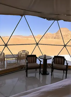 a tent with chairs and a table and a view of the desert at Rum Honeymoon Camp in Wadi Rum