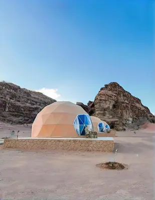 two domes in a desert with rocks in the background at Rum Green Camp in Wadi Rum
