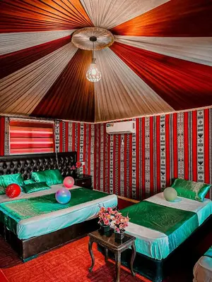 a room with two beds and a table with flowers at Rum Green Camp in Wadi Rum