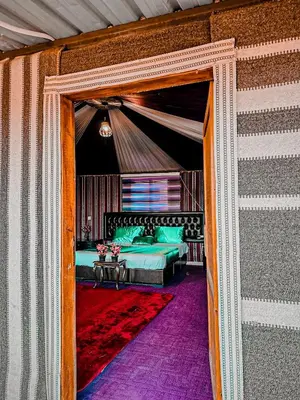 a doorway into a tent with a bed and a table at Rum Green Camp in Wadi Rum