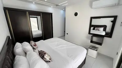 a bedroom with a white bed and a mirror at شقة بثلاث غرف نوم الجاردنز عمو سامي in Amman