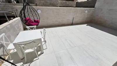 a patio with a hammock and a chair and a table at شقة بثلاث غرف نوم الجاردنز عمو سامي in Amman